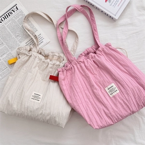 Gros plan sur la texture plissée et les bords volantés des sacs cabas beige et rose