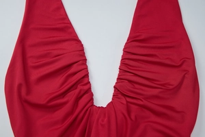 Détail de fronces sur une robe rouge à décolleté en V profond en tissu extensible