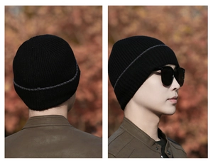 Detail of black ribbed knit beanie with grey stripe showing thick winter texture and stitch