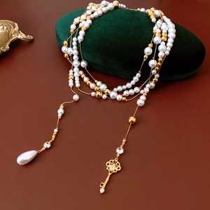 Detail of French vintage multi-layer pearl necklace with golden key and water drop pendant