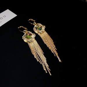 Makro-Detail von Vintage-Gold-Ohrringen mit grünen Kristallen und langen Fransenketten