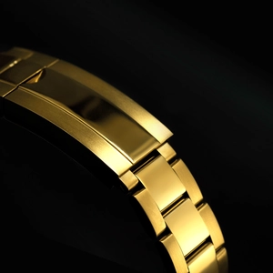 Detail shot of golden metal watch strap clasp showing premium brushed and polished finish