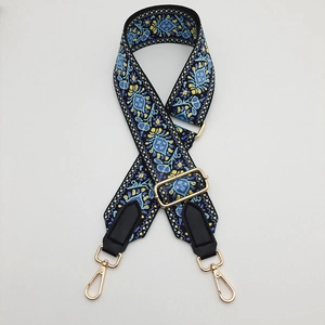 Detail of embroidered canvas strap with ethnic floral patterns and gold metal lobster clasps