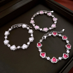 Detailed view of three heart-shaped zircon bracelets in white, pink and red colors