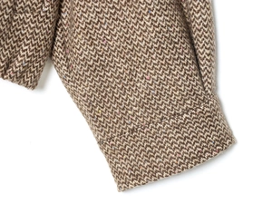 Dettaglio ravvicinato del tessuto in tweed marrone con trama di lana della giacca