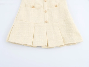 Detailansicht des beigen Tweed-Minikleides mit Goldknöpfen und Faltenstruktur