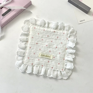 Close-up of white square napkin with pink heart pattern and delicate lace edges