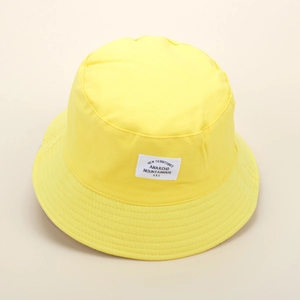 Detailed top view of a bright yellow cotton bucket hat with a minimalist white fabric patch