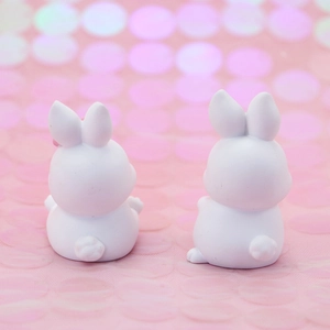 Rear view of two cute white rabbit figurines with soft pink bokeh background effect