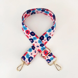 Detail of adjustable floral strap with red and blue flowers and golden metal buckles