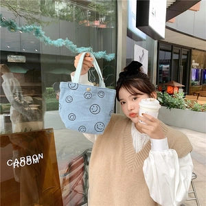 Blue corduroy tote bag with black smiley faces shown in an outdoor lifestyle setting
