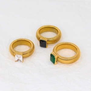Detailed shot of three gold ribbed rings with clear, black, and green rectangle stones