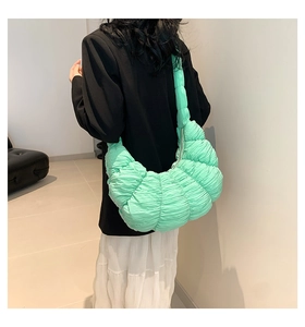 Detailed back view of a mint green pleated cloud bag styled with a black blazer
