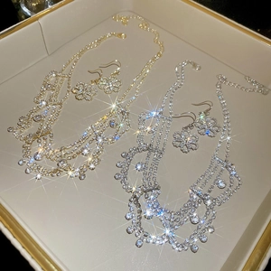 Detailed close-up of crystal flower necklace and earrings in gold and silver finish