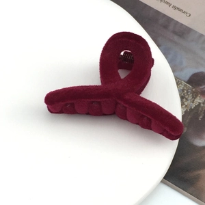 Close-up of deep red flocked velvet hair clip with twisted knot design on white tray