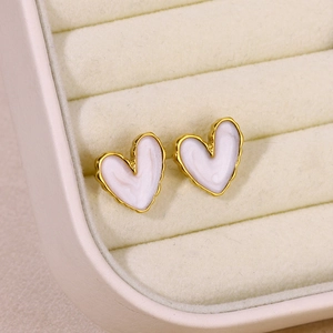 Detail of heart-shaped gold studs with white marble inlay in a jewelry box