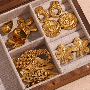 Macro shot of gold-plated petal earrings and geometric jewelry in a wooden box