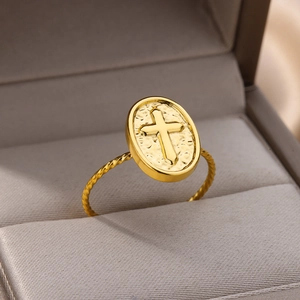 Detailed close-up of 18k gold plated ring with cross emblem and twisted band in a box