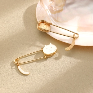 Cute gold cat safety pin brooches with white enamel details and crescent moon charms