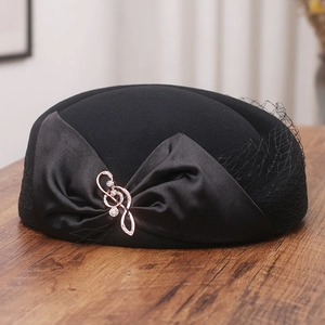 Detail of wool beret with satin bow, rhinestone music note brooch and black mesh veil