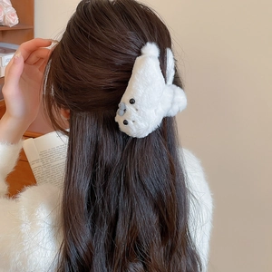 Detail of a white plush seal hair claw clip styled on long brown hair for a cozy winter look
