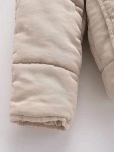 Close-up of quilted beige padded jacket cuffs showing twill fabric and thick stitching