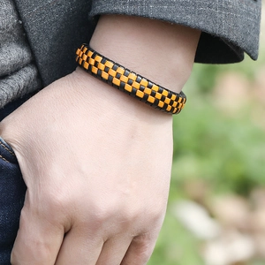 Braided leather bracelet with orange and black checkered pattern on model wrist