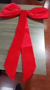 Close-up of a large red velvet decorative bow with long ribbons on a wooden surface