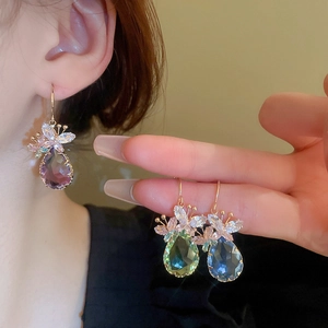 Detail of teardrop gemstone earrings with zircon butterfly accent and golden hook