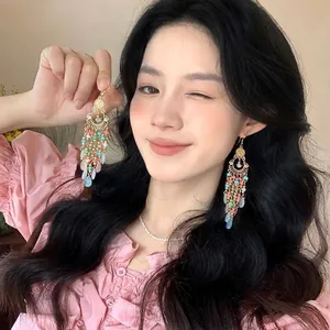 Detail of bohemian long tassel earrings with colorful beads and gold metal chain drops
