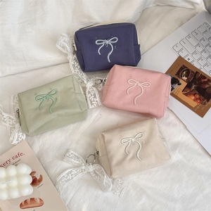 Flat lay of canvas cosmetic bags in four colors with bow embroidery and lace zipper
