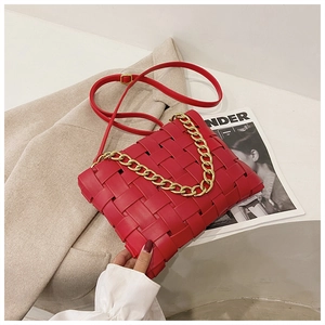 Detail of red woven leather handbag with chunky gold chain strap on minimalist background