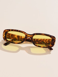 Close-up of tortoise shell rectangular frame with yellow tinted lenses on beige background