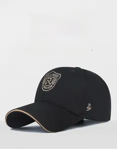 Close-up of black baseball cap with embroidered shield logo and brown brim trim