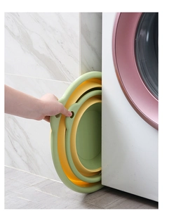 Space-saving foldable silicone washbasin being stored in a narrow gap next to a washing machine