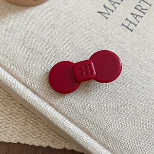 Macro shot of dark red resin bow hair clip with glossy finish and embossed text detail