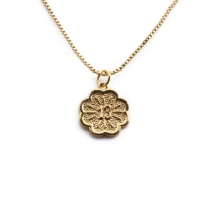 Detailed macro of gold-plated flower pendant featuring embossed number 13 and ray texture