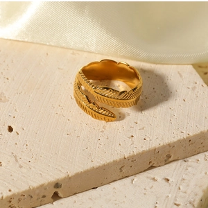 Macro shot of gold feather ring texture on stone surface with elegant silk backdrop
