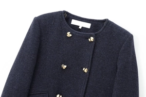 Gros plan sur la texture du tweed bleu marine et les boutons dorés de cette veste