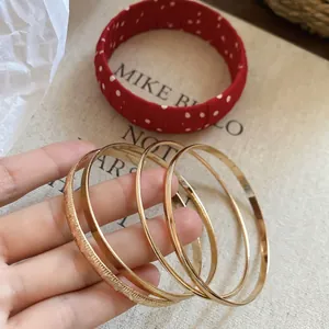 Close-up of four gold minimalist geometric bracelets featuring smooth and textured finishes