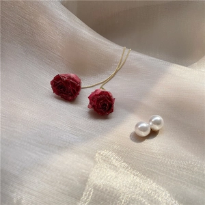 Elegant red rose earrings with long gold chains and white pearls on silk fabric
