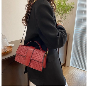 Detail of red woven texture shoulder bag with gold hardware and leather strap