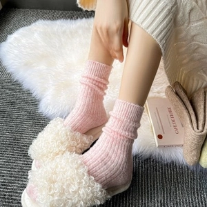 Detailed texture of pink ribbed knit wool socks paired with white fuzzy fleece slippers