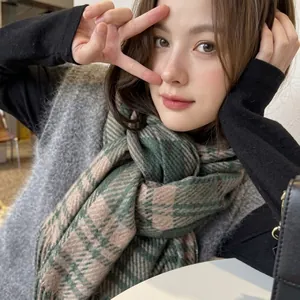 Detail of soft green and beige plaid scarf worn with a grey knit vest for a cozy look