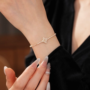 Sparkling zircon flower charm bracelet with adjustable gold chain on female wrist