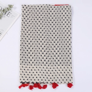 Detailed flat lay of beige cotton scarf with black polka dots and red fringe tassels