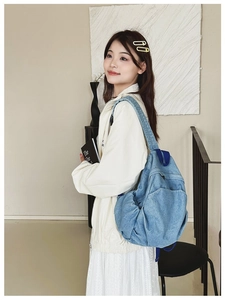 Detail view of light blue denim backpack with adjustable shoulder straps and soft texture