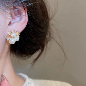 Detailed close-up of elegant gold-plated pearl flower earrings with zircon on a model