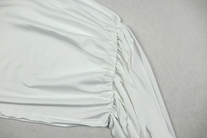Close-up detail showing the white gathered fabric and ruched texture of the backless dress