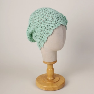Detailed knit texture of light green crochet beanie with a side flower decoration